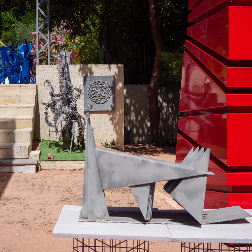 Angular metal figure sculpture in the garden, with red architectural element