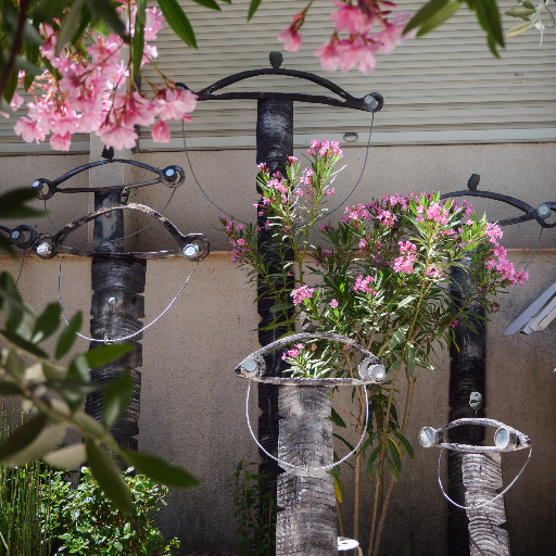Hanging metal sculptures among flowers and foliage