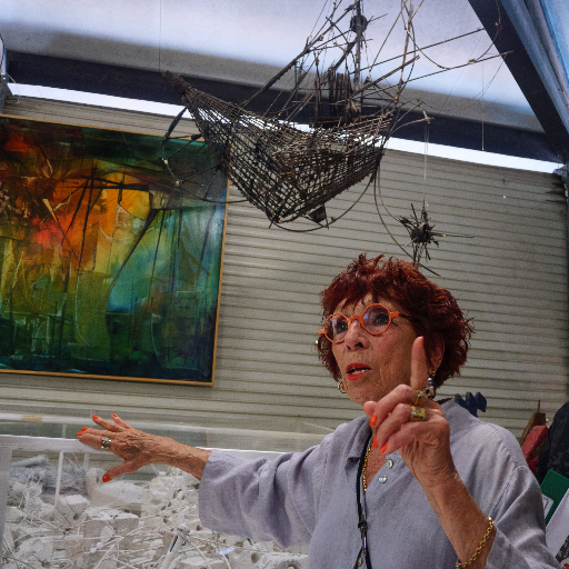 Madeleine Molinier in her studio, gesturing — painting behind her