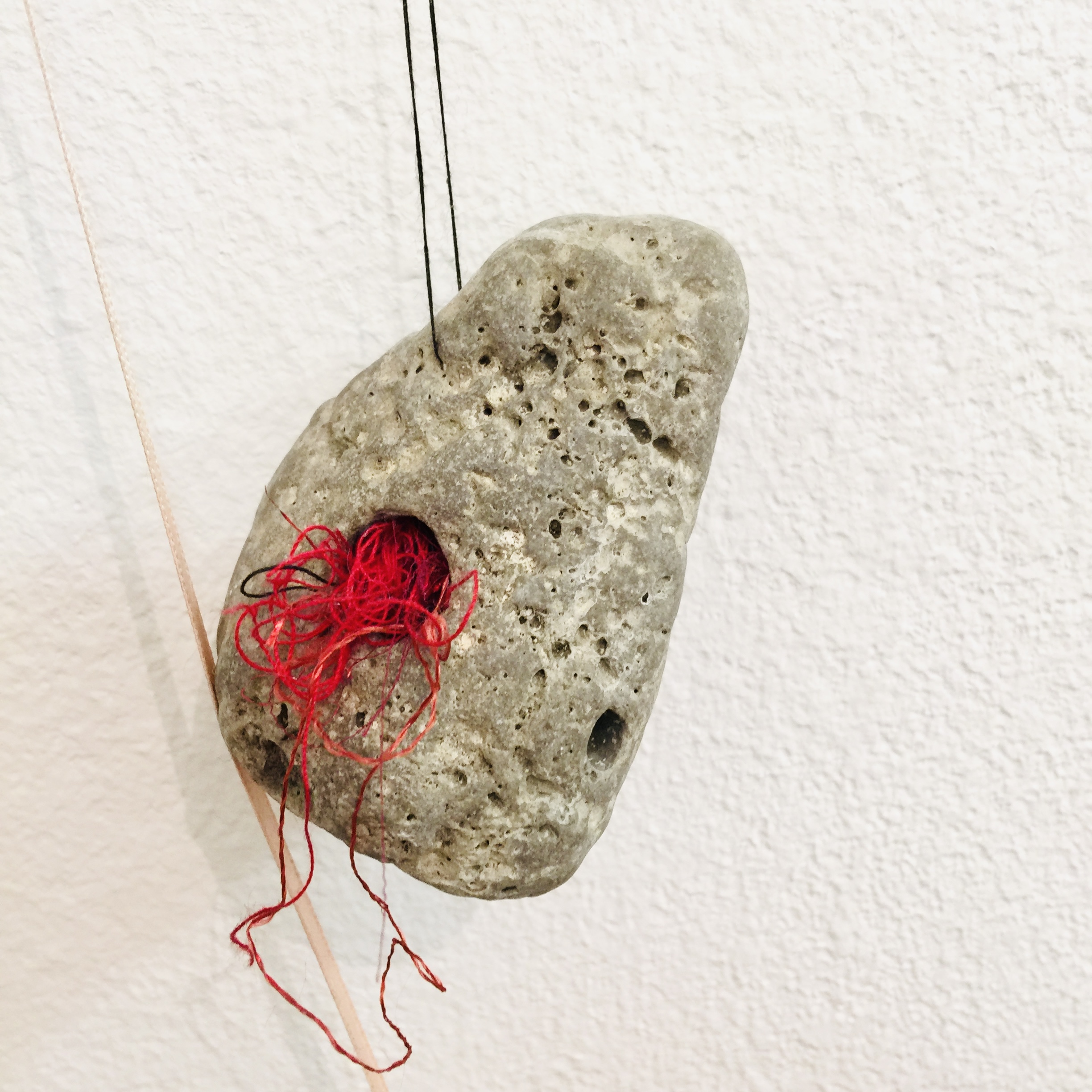 Object — stone with red thread
